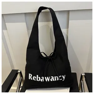 Detail of black canvas tote bag with Rebawancy text and drawstring bow decoration