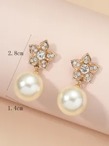 Detail of elegant gold flower drop earrings with rhinestones and large white pearls