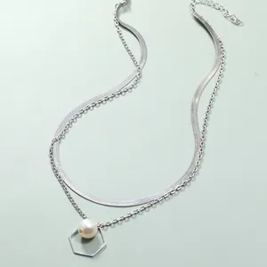 Detalle de collar de doble capa plateado con colgante hexagonal de perla blanca