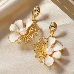 Golden flower drop earrings with white shell petals and a pearl center on silk