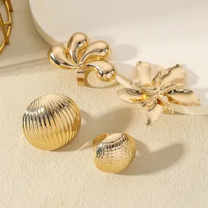 Detailed view of four chunky gold rings with floral and geometric textured patterns
