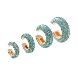 Lot de quatre bagues d'oreille dorées en forme de C avec zircons bleus sur fond blanc