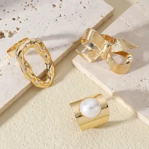 Detailed view of three gold-plated rings with bow design, textures, and large faux pearl