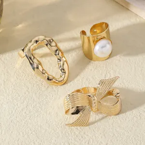 Detailed close-up of gold-plated rings featuring irregular textures, pearls, and bow designs