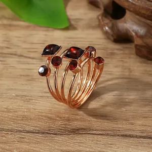 Close-up of rose gold spiral scarf ring with deep red gemstones on wooden table