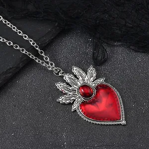 Gothic red heart pendant with silver crown detail on black lace and stone background