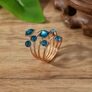 Macro-opname van meerlagige roségouden ring met blauwe stenen op hout