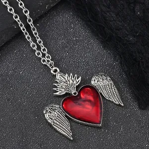 Close-up of a Gothic red heart necklace with silver wings and dark lace accents
