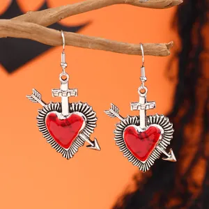Gothic-Ohrringe im Detail mit rotem Marmorherz, einem Kreuz und einem Pfeil-Design