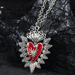 Macro detail of gothic sacred heart pendant with red enamel and silver starburst rays