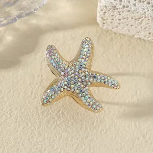 Anello a stella marina dorata con strass colorati su uno sfondo di corallo strutturato
