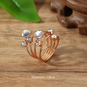 Detail van gelaagde roségouden spiraal sjaalring met imitatiediamanten op hout
