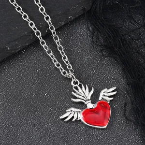 Macro shot of Gothic red enamel winged heart pendant with silver chain on dark stone