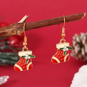 Detailed view of red Christmas stocking earring with holly leaves and crystal accents