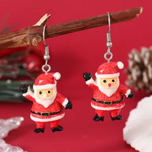 Close-up of glittery Santa Claus drop earrings hanging on a natural wooden branch