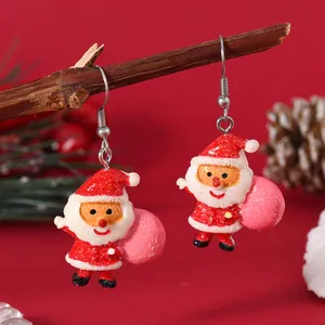 Detailed view of festive Santa Claus earrings with glitter resin on a holiday branch