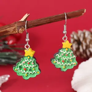 Detailed close-up of glittery green Christmas tree earrings hanging on a natural branch