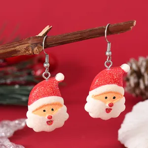 Close-up of Santa Claus hook earrings hanging on branches with festive red background