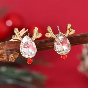 Macro detail of Christmas reindeer stud earrings with crystal antlers on a rustic wood branch