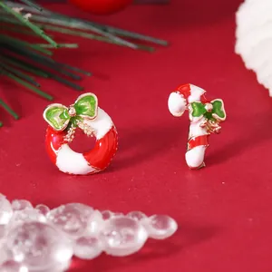 Close-up of asymmetrical Christmas earrings with candy cane and wreath enamel designs