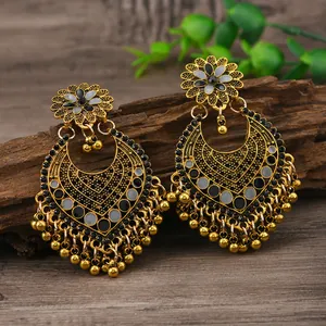 Nahaufnahme von Vintage-Bohème-Goldohrringen mit Blumenmotiven und Glockenquasten
