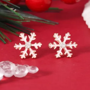 Detailed view of rose gold snowflake earrings with white enamel and center rhinestone