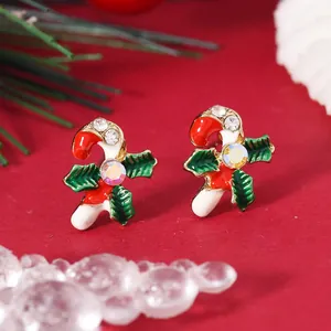 Detail of Christmas candy cane earrings with holly leaves and sparkling crystal accents