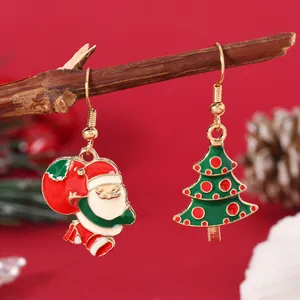 Detail of asymmetric Christmas earrings with Santa and green tree on wooden branch