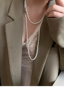Detail of layered long pearl necklace with high luster on a khaki blazer outfit