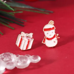 Detail of Christmas snowman and gift box enamel stud earrings on festive background