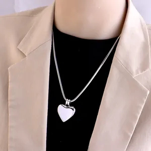 Elegant silver heart pendant necklace with snake chain on model wearing beige blazer
