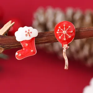 Detailed macro shot of festive red enamel Christmas stocking and snowflake balloon earrings