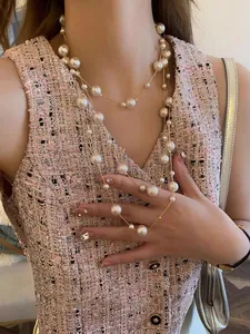Detail of layered pearl sweater necklace featuring gold leaf accents on elegant chain