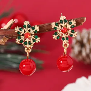 Close-up of gold snowflake earrings with red and green rhinestones on a festive background