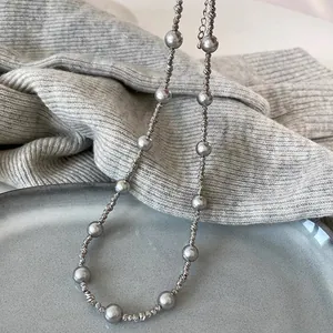 Detail of grey pearl long necklace on knit sweater with adjustable lobster clasp