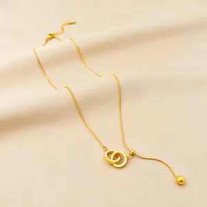 Elegant gold-tone snake chain necklace with interlocking double ring pendant and tassel bead