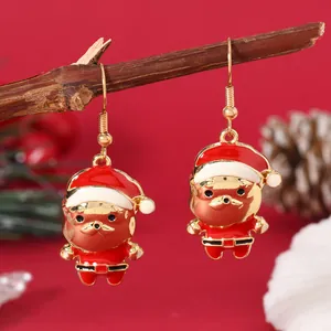 Detailed close-up of golden alloy Santa Claus earrings with red enamel on a wooden branch