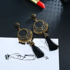 Detailansicht von Boho-Ohrringen in Gold mit schwarzen Seidenquasten und Perlenbesatz