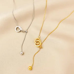 Detail of gold and silver minimalist interlocking ring tassel necklaces on textured fabric