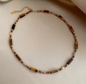 Détail macro des perles œil de tigre et du fermoir mousqueton doré du collier