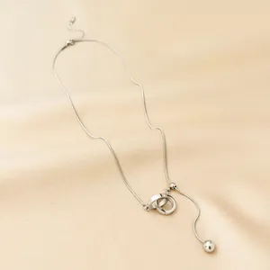 Detail of silver Y-shaped tassel necklace with interlocking rings on silk fabric