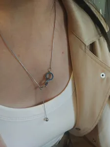 Detail of interlocking silver rings necklace with Roman numerals on adjustable chain