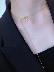 Close-up of a gold Y-shaped tassel necklace with circular link detail on a model neck