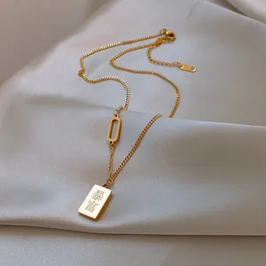 Vue détaillée du pendentif rectangulaire doré avec gravure Bao Fu sur satin