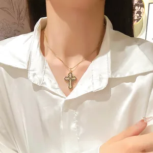 Close-up of a gold cross necklace with white zircons and black trim on a silk shirt