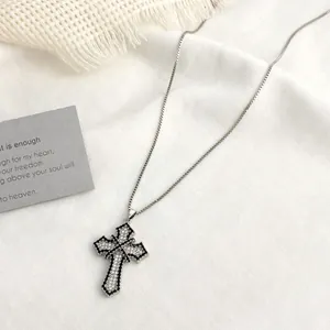 Macro detail of gothic cross pendant with white cubic zirconia and black bead outline