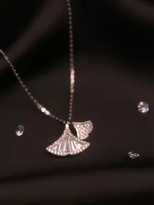 Vue macro du pendentif feuille de ginkgo argenté avec sertissage de zircons brillants