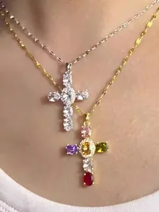 Détail de colliers croix en argent et or avec zircons colorés portés par un modèle