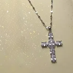 Gros plan d'un collier pendentif croix en argent avec de grands zircons ovales