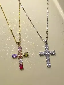 Détail de deux pendentifs croix avec zircons colorés et clairs sur chaînes en or et argent